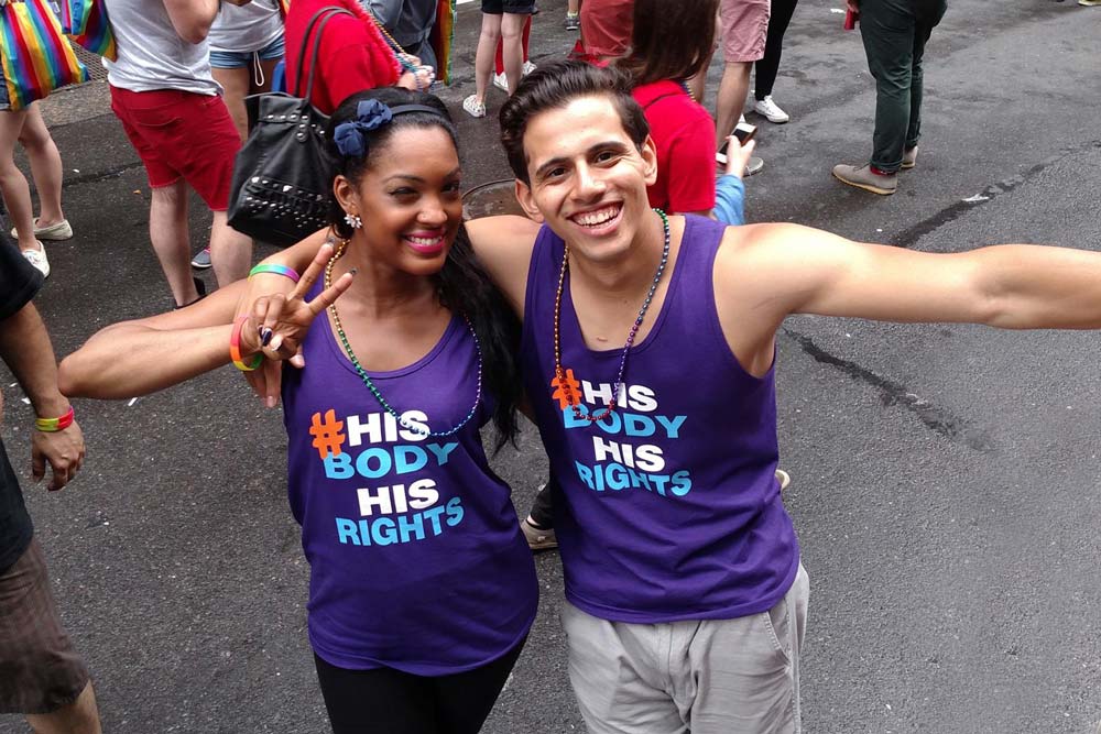 Couple wearing purple shirts that say 'His Body, His Right'